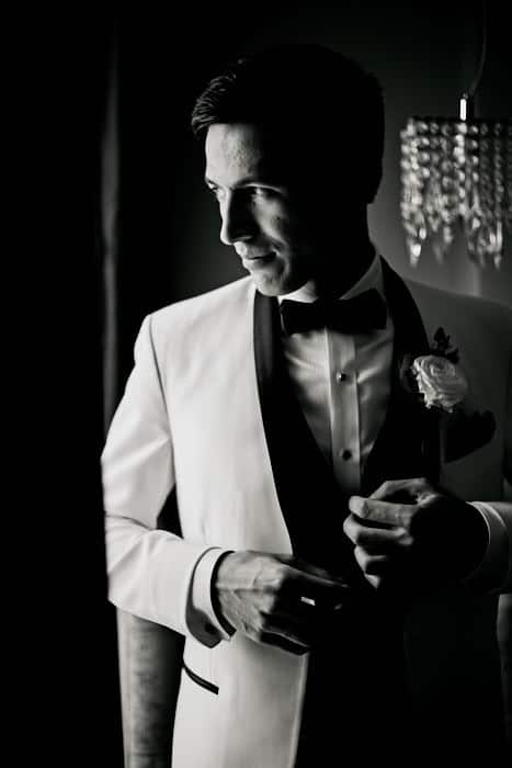 Man in tuxedo looking out window.