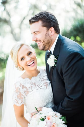 Bride and groom smiling in wedding attire.