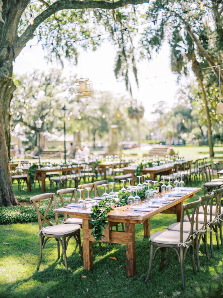 Outdoor wedding reception with wooden tables.